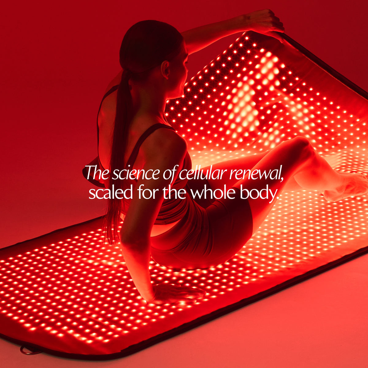 Woman seated on an illuminated Restora+ LED mat, lifting the upper panel of the pod