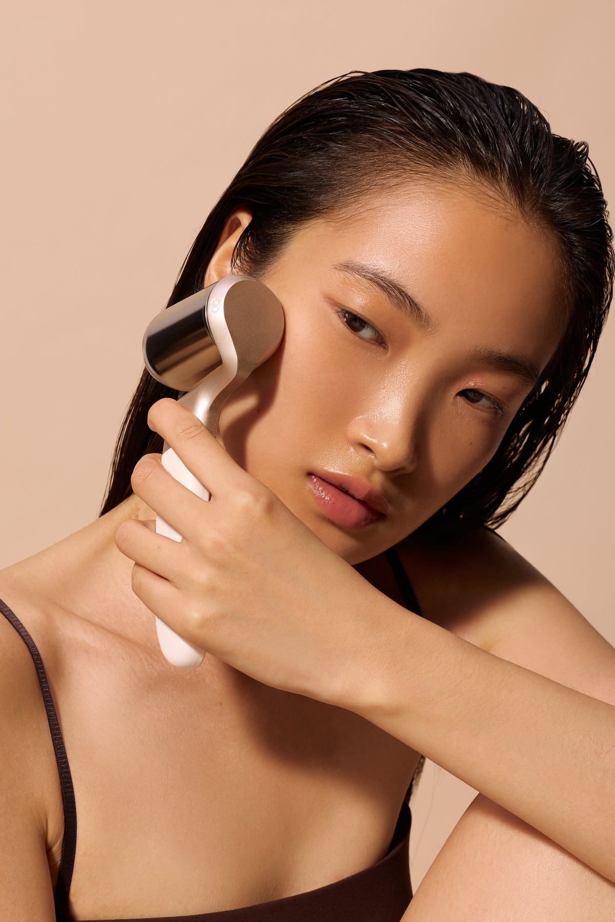 Model holding Project E Beauty facial sculpting device against cheek.
